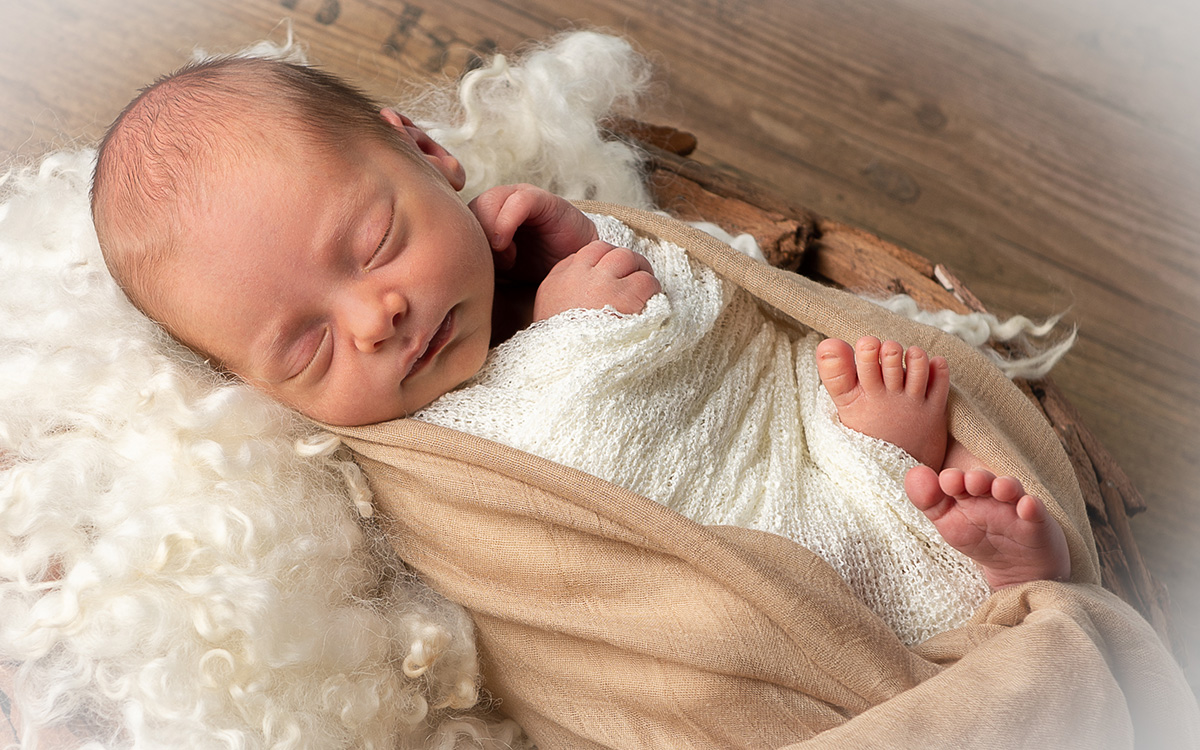 Ein Baby, welches in eine braune Decke gewickelt ist und schläft.