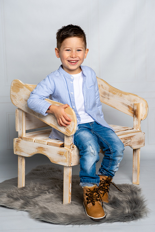 Junge auf einem Stuhl lächelt in die Kamera.