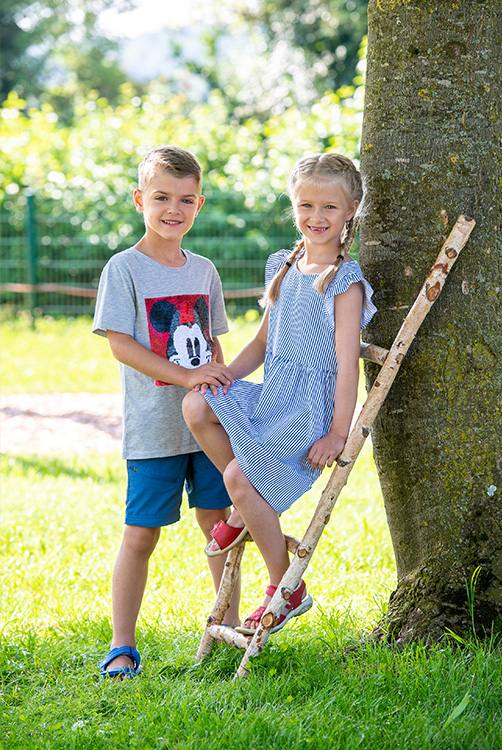 Mädchen und Junge an einer Leiter aus Holz.