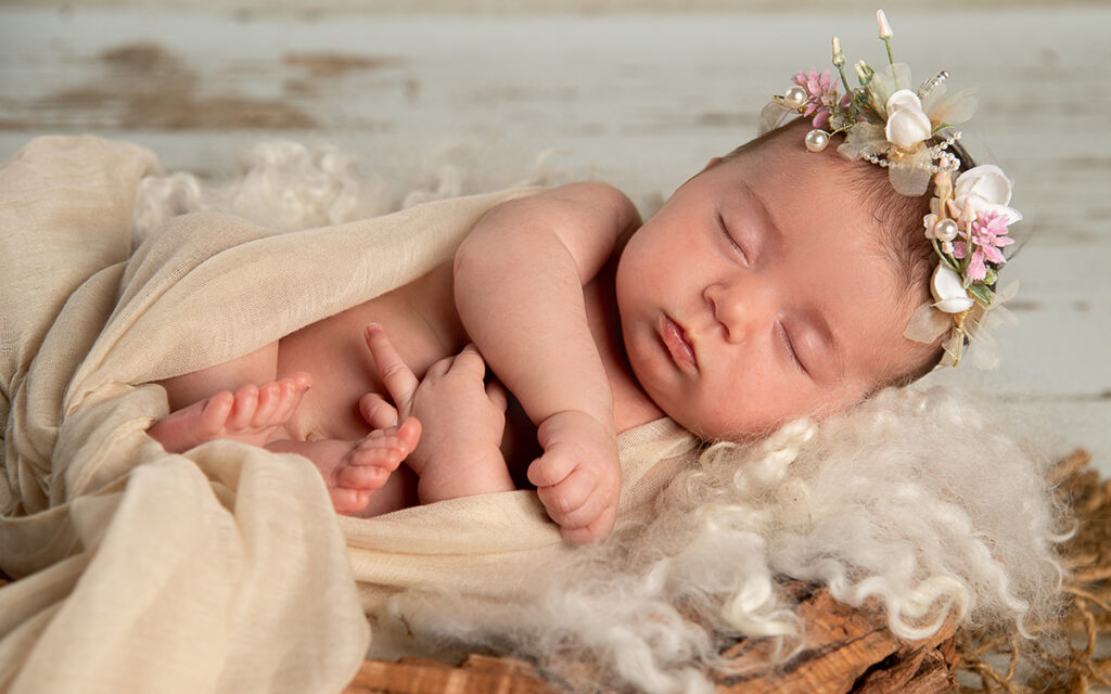 Schlafendes Baby mit Blumenschmuck auf dem Kopf